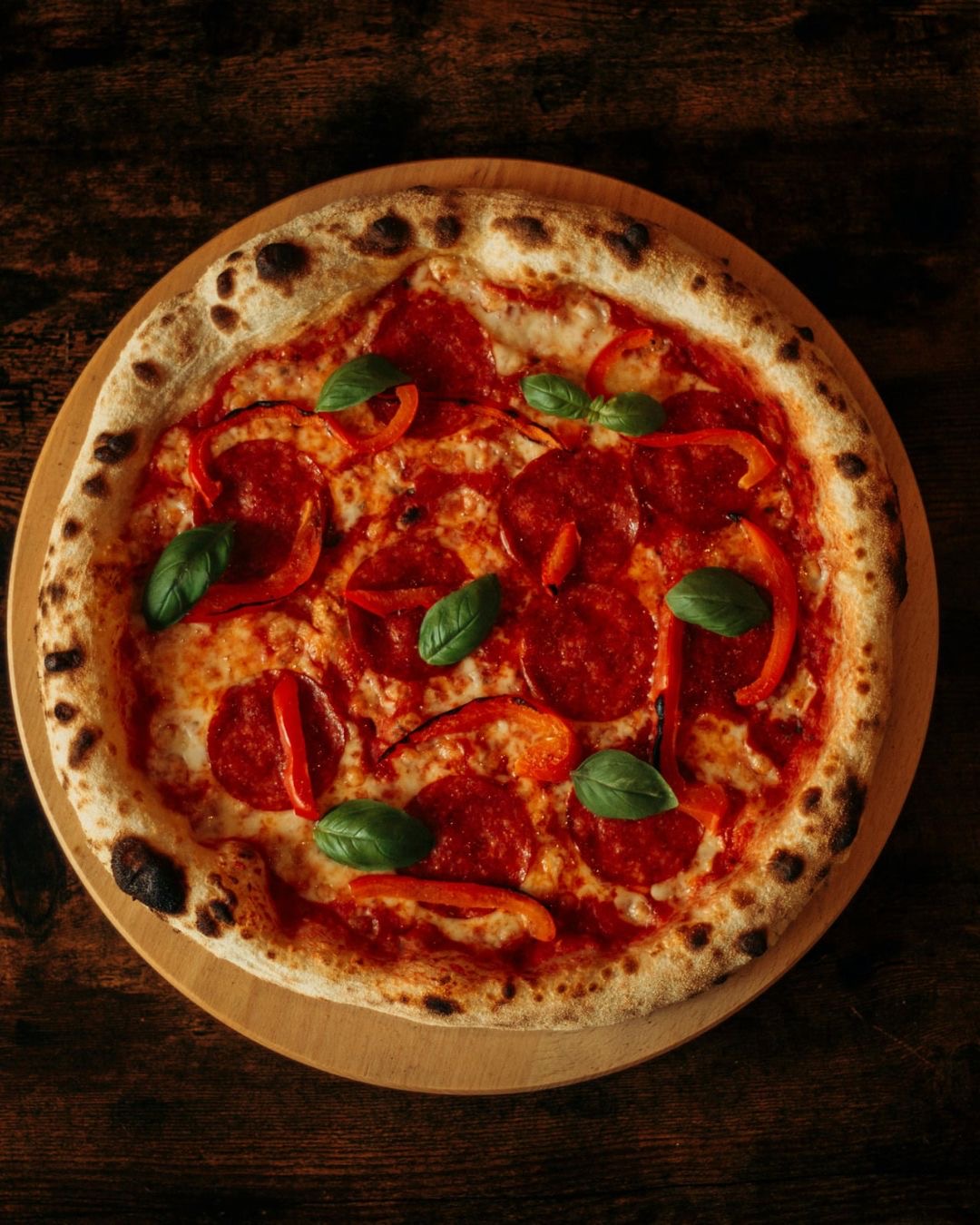 Pepperoni pizza with red peppers and fresh basil
